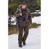 Muž v outdoorovom oblečení značky Merkel Gear kráča po zasneženej krajine. Má na sebe pánske nohavice Merkel Gear Paläarktis Gen. II, ktoré sú vetru a vodeodolné, s formovanou oblasťou kolien a vnútornými gamašmi. Na sebe má aj bundu a klobúk, nesie batoh a ďalekohľad.